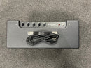 Guitar amplifier with control panel and power cord on a gray surface